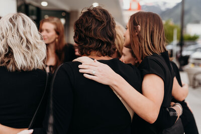 Two women with their arms around one another in support