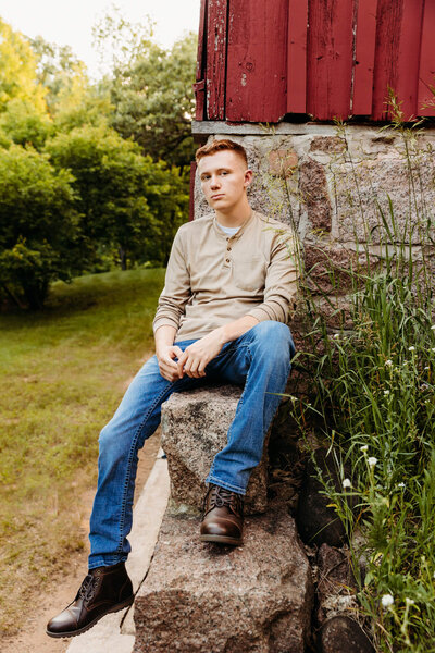 teen boy sitting against a barn for senior session