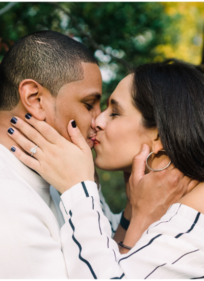 couple kissing in a park with their hands on each other faces