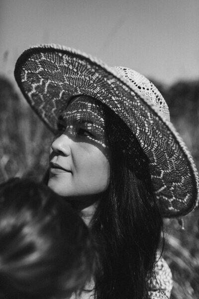 Black and white close up of woman wearing straw hat.