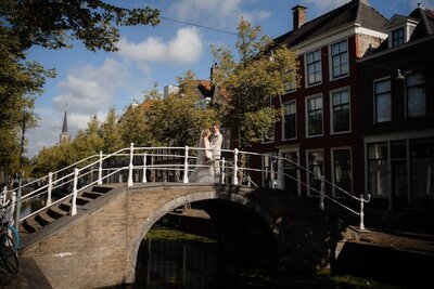 Getrouwd koppel op brug over gracht in Delft, vastgelegd door trouwfotograaf Julia de Groot