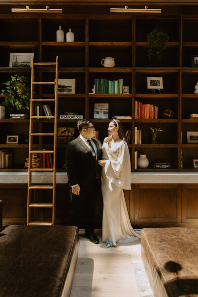 bride and groom in front of floor to ceiling mahogany library wall