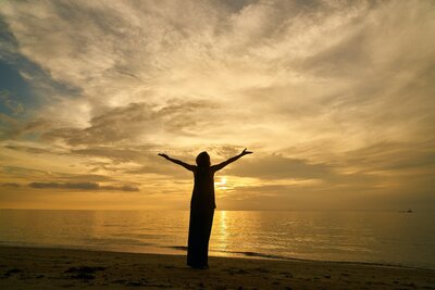 A symbol of overcoming: the silhouette of a person with arms outstretched, greeting the rising sun