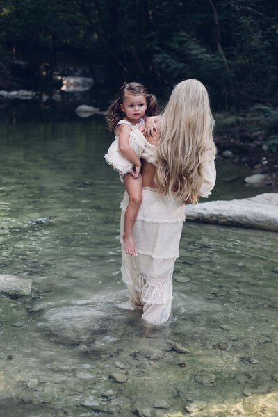 A woman holding a child in a river captured by a skilled destination wedding photographer.