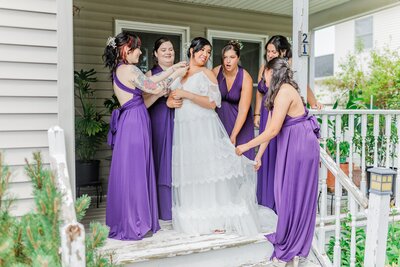 bride with bridesmaids on house porch during wedding photo session in albany ny 