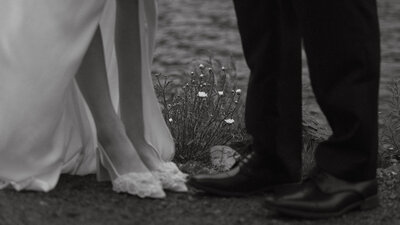 black and white photo of bride and grooms shoes while they are standing next to each other