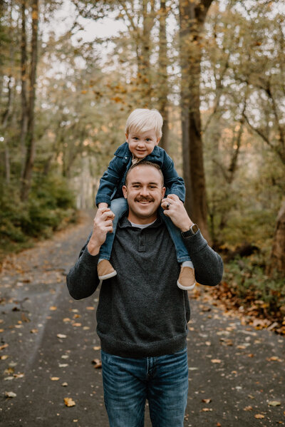 Dad wearing gray and blue with son on his shoulders wearing blue in Ellicot City Maryland