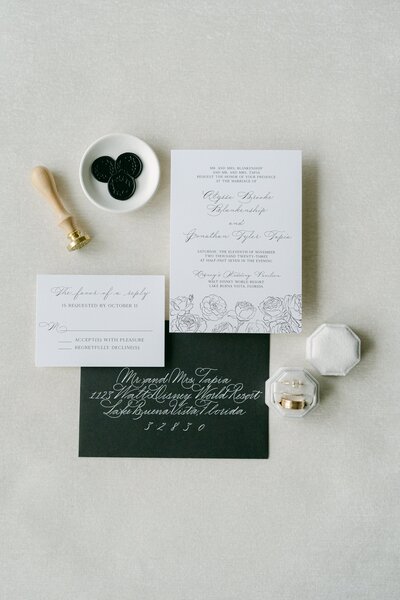 Wedding invitation collection featuring dark green envelopes, white cards, and delicate floral details