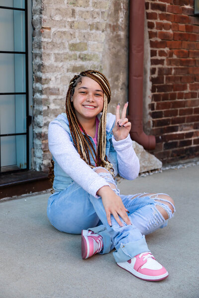 Senior picture of a girl with beautiful braids on Historic Commercial Street in Springfield, MO.  Captured by senior photographer Dynae Levingston