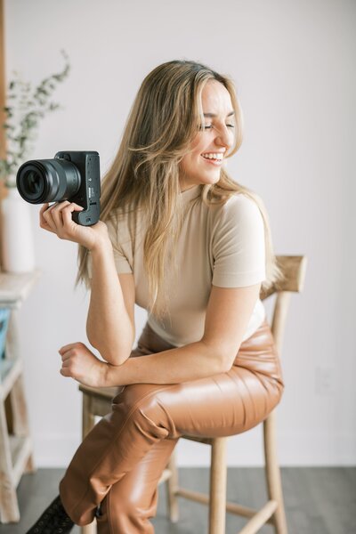 woman sitting in chair holding camera smiling down