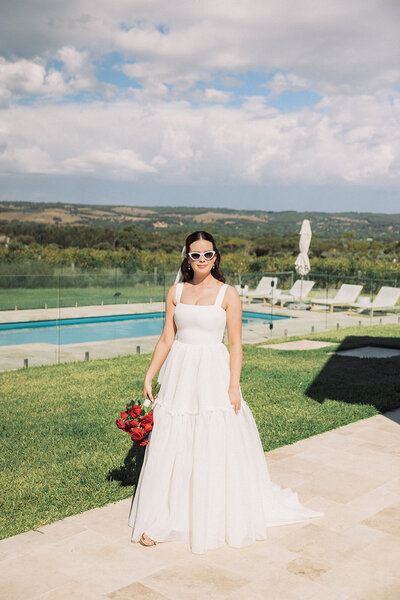 bride holding flowers by pool on wedding day
