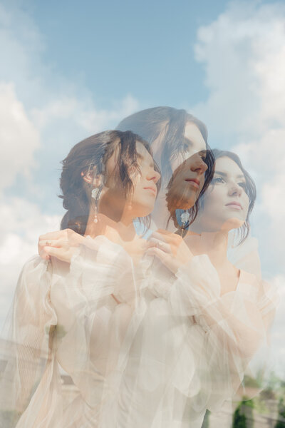 Dreamy triple-exposure bridal portrait against a soft blue sky