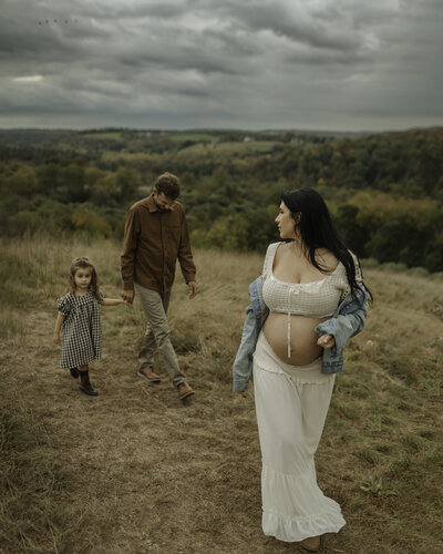 mom posing with baby bump while walking in front of family