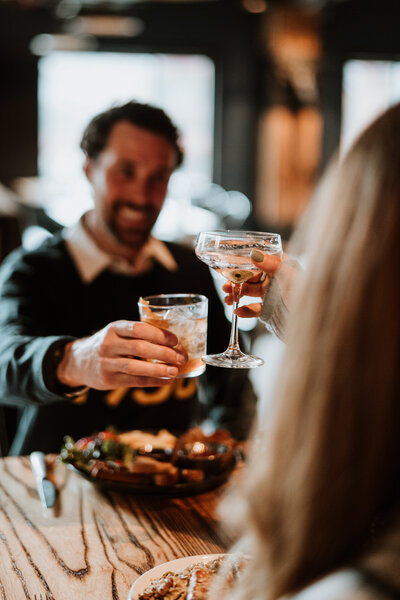 Branding photo of a couple toasting drinks at a cozy restaurant, captured by Breckenridge content creators.