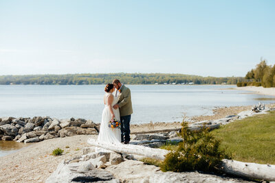 bride and groom hugging with Lake Michigan in the background and rocks and grass