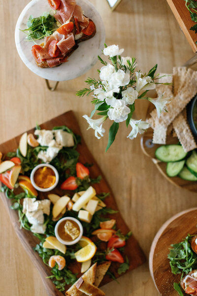 Charcuterie planner with flowers on a wooden table.