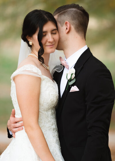 A catholic couple shares an intimate moment during fall portraits following their catholic wedding Mass at St. Thomas Aquinas Catholic church in Cookeville, Tennessee