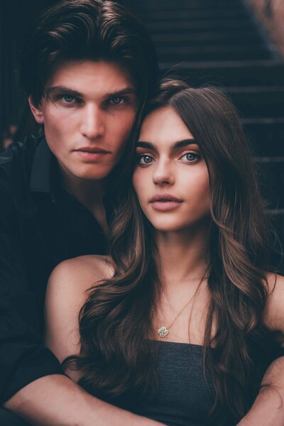 A young couple with dark hair sit closely together and look into the camera of Shreveport engagement photographer, Britt Elizabeth Photography.
