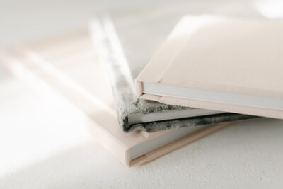 Close-up of handcrafted heirloom photo albums stacked on a light colored table in Kansas City, ready to preserve family memories beyond digital screens.