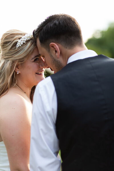 Couple stand nose to nose as they look into each others eyes. the bride who's profile is seen the most is smiling