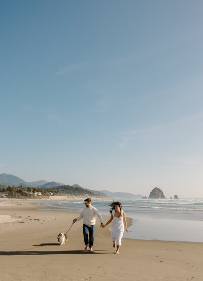 Couple runs along the coast with their dog during their anniversary session.