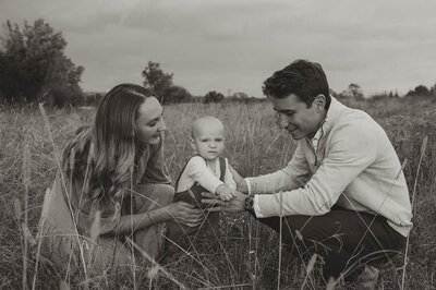 Black and white photo of a family sharing a joyful moment together in a field during a Charlotte family photography session.