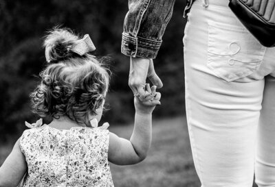 Black and white photo of little girl holding mom's hand