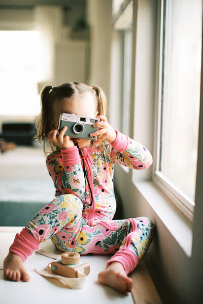 Britni Dean's daughter wearing pajamas and holding a camera
