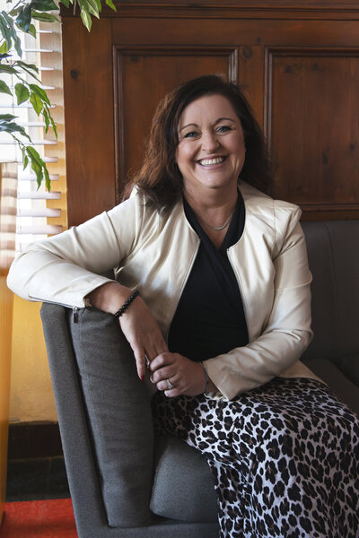 Professional headshot of a woman seated and smiling confidently during a brand photography session