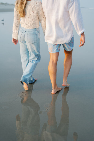 A couple holding hands and walking on the beach in Avalon, NJ