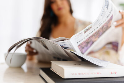 Newspaper in focus with Abby Manawes out of focus in the background