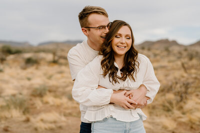 A couple hugs in the desert while laughing