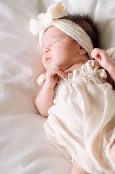 Close-up of a newborn baby resting on a soft white blanket during a Northern Virginia lifestyle session captured by a family photographer. 