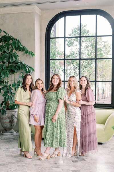 Photo of the Spell Events wedding planning team sitting around a white couch in front of a floral wall