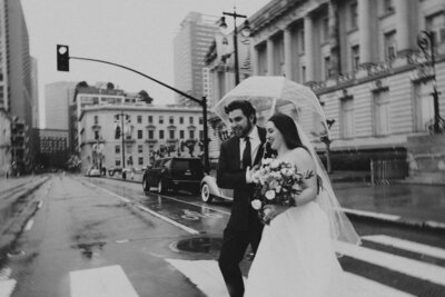 bride and groom crossing street in the rain