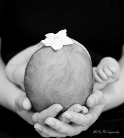 a mother holding her newborn daughters head in her hands photographed by Millz Photography in Greenville, SC