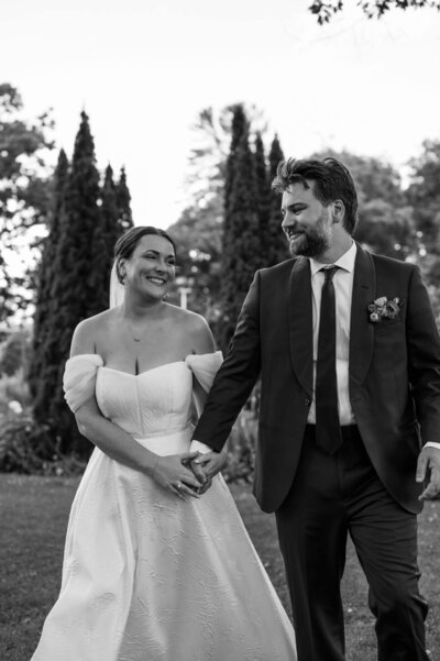 A black and white photo of a bride and groom smiling at each other on their wedding day.