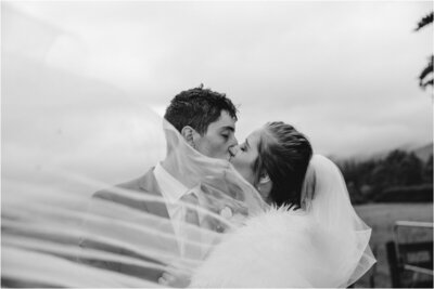 black and white bride and groom behind veil