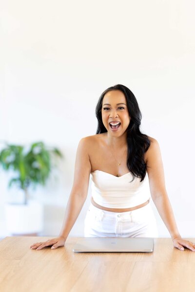 Content creation photographer in Dallas, TX, wearing a white elegant outfit and smiling confidently during a branding photoshoot