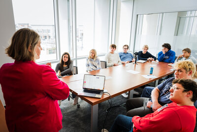 Mya Anderson leads a meeting with several parents and family members seated around a conference table in a bright room, sharing tips on how to Set Your College Student Up for Success