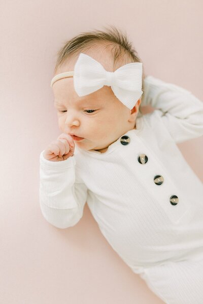 A baby girl wearing a white bow photographed by Katelyn Ng, Indianapolis Newborn photographer.
