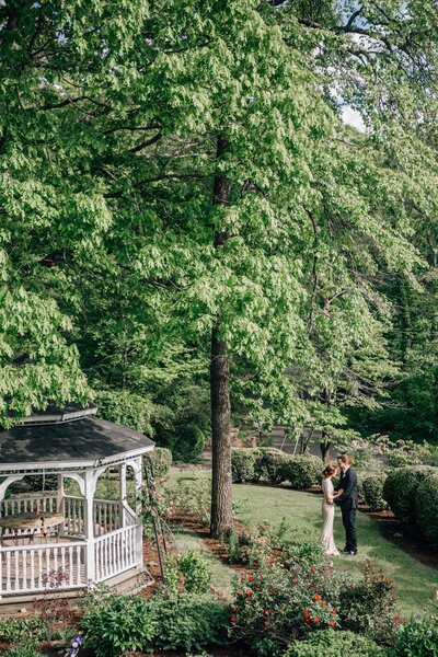 bride and groom standing outside next to a gazebo for their outdoor wedding day in Virginia with groom kissing bride on the forehead captured by best Hampton Roads wedding photographer