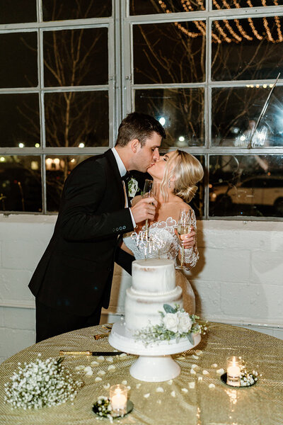 newlyweds kiss behind cake