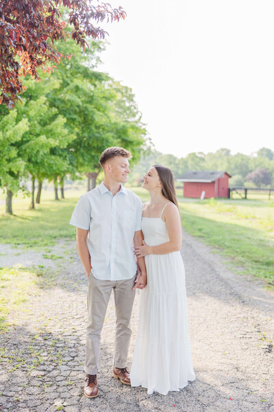 Man holds onto woman and she smiles over her shoulder as the golden sunset is behind them. Taken at a winery in Kentucky by cincinnati based wedding photographer.