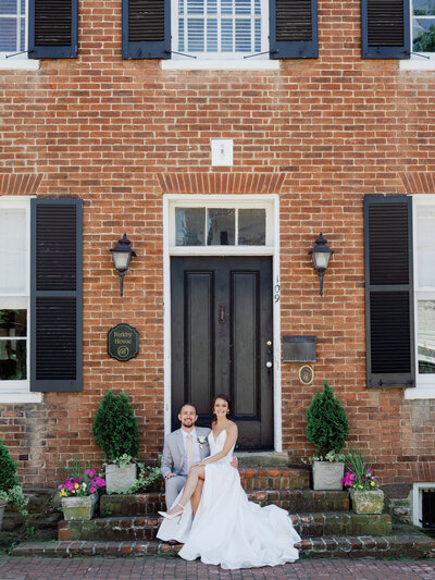 Photo of couple sittin on steps in front of manor house