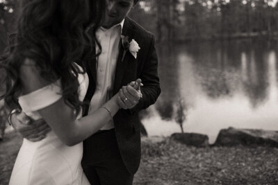 Bride and groom dancing and holding hands by lake