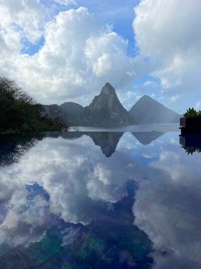 A stunning view of the Piton mountains in St. Lucia, reflected in a sleek infinity pool. The picturesque landscape highlights the beauty of a luxury destination wedding setting.