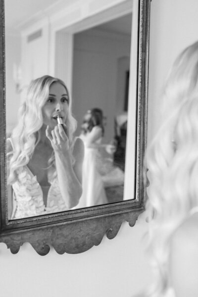  Bride applying lipstick in antique mirror, showcasing the intimate, editorial detail style of Fine Art Wedding Photography Seattle.
