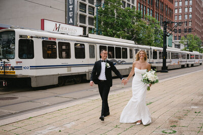 Newlyweds embracing in front of the expansive windows and exposed beams of The Arbor Loft’s loft-style interior.
