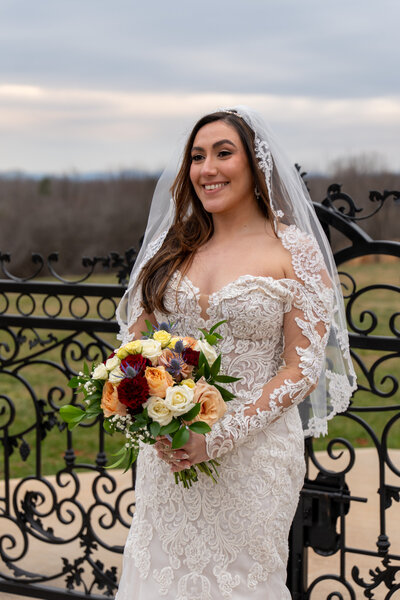 A person in a wedding dress holding a bouquet and smiling 